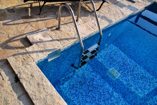 Küpeşte havuzu üzerinde. Merdiven tropikal Resort'ta Yüzme Havuzu. Havuz korkuluk görüntüleyin. Güneşli yansıması ile su Yüzme Havuzu. Çelik Küpeşte, yüzme, yaz, seyahat. Giriş havuzuna Küpeşte ile.
