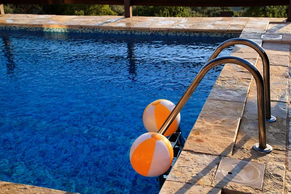 Duas bolas infláveis brancas amarelas do ar de borracha e brinquedo para a piscina na água azul transparente. Bolas de praia multi-coloridas flutuando na água na piscina azul para o conceito relaxar viagem de férias . — Fotografia de Stock