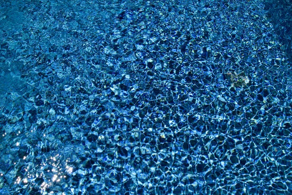 Piscina fondo caustici ondulazione e flusso con onde di sfondo. Superficie della piscina blu, sfondo di acqua in piscina. Acqua limpida piscina azzurra increspature con riflessi solari . — Foto Stock