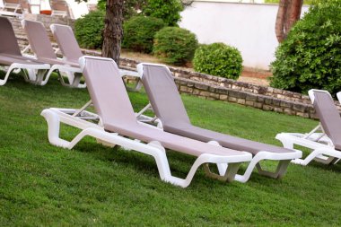 Egzotik plaj deniz güneşlenme için şezlong üzerinde ve lüks resort Otel'in tropikal Bahçe çim dinlenin. Turistler için bekleyen'ın bahçesinde şezlong. Yaz sezonu pastoral sahil.