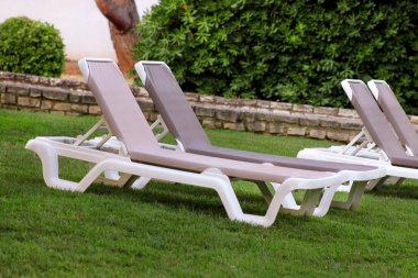 Egzotik plaj deniz güneşlenme için şezlong üzerinde ve lüks resort Otel'in tropikal Bahçe çim dinlenin. Turistler için bekleyen'ın bahçesinde şezlong. Yaz sezonu pastoral sahil.