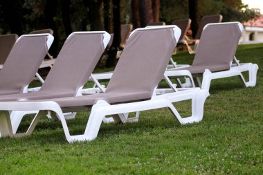 Egzotik plaj deniz güneşlenme için şezlong üzerinde ve lüks resort Otel'in tropikal Bahçe çim dinlenin. Turistler için bekleyen'ın bahçesinde şezlong. Yaz sezonu pastoral sahil.
