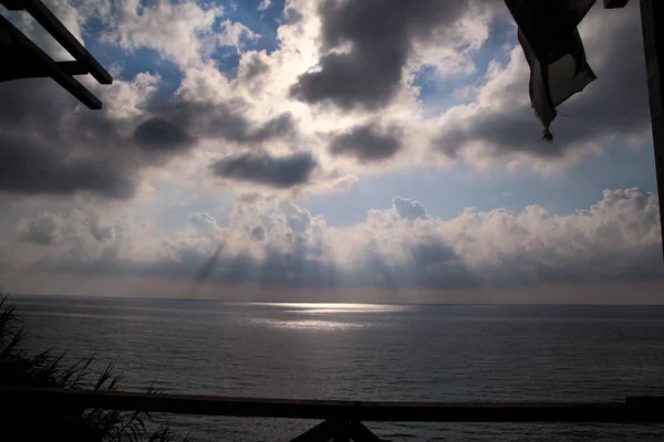Dramatic sunset skies with grey clouds with lines of sun to tropical mediterranean sea. Beautiful natural environment. Panorama landscape and horizon of sun beams over calm ocean, amazing view scene.