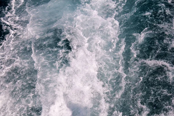 Turbulentie gemaakt door schuim van het zeewater van een snelle jacht op de oppervlakte van de zee. Blauwe zee golven met veel schuim van de zee. Oppervlakte van zee met golven, splash, schuim en bubbels, blauwe achtergrond en behang. — Stockfoto