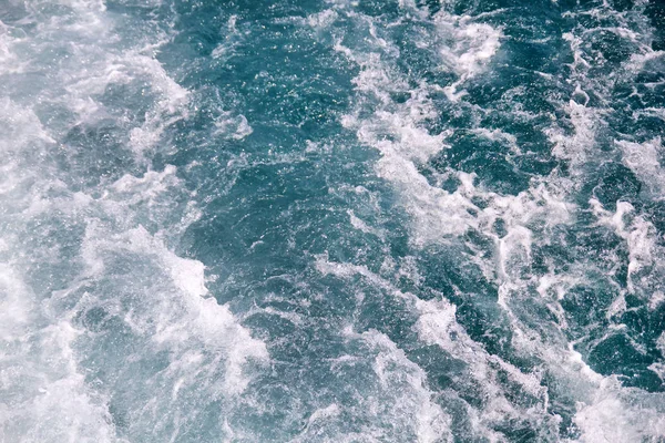 Turbulentie gemaakt door schuim van het zeewater van een snelle jacht op de oppervlakte van de zee. Blauwe zee golven met veel schuim van de zee. Oppervlakte van zee met golven, splash, schuim en bubbels, blauwe achtergrond en behang. — Stockfoto