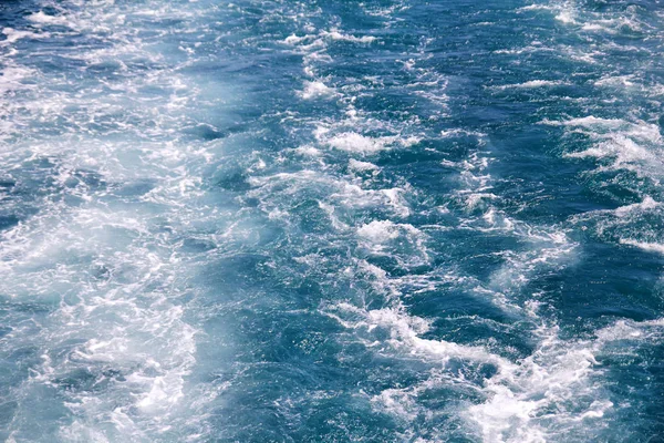 Turbulentie gemaakt door schuim van het zeewater van een snelle jacht op de oppervlakte van de zee. Blauwe zee golven met veel schuim van de zee. Oppervlakte van zee met golven, splash, schuim en bubbels, blauwe achtergrond en behang. — Stockfoto