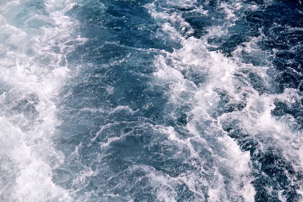 Turbulenzen, die durch Schaum des Meerwassers von einer Hochgeschwindigkeitsjacht auf der Meeresoberfläche verursacht werden. blaue Meereswellen mit viel Meeresschaum. Meeresoberfläche mit Wellen, Spritzer, Schaum und Blasen, blauem Hintergrund und Tapete. — Stockfoto