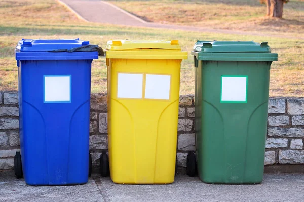 Trash can, garbage bin, recycling bin in tourist complex resort, waiting to be picked up by garbage truck. Blue, yellow and green containers for waste sorting, sort garbage for metal, paper and glass. — Stock Photo, Image