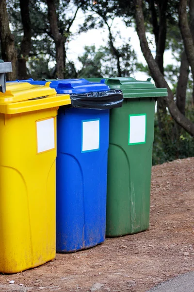 Tempat sampah, tempat sampah, tempat sampah di resor pariwisata, menunggu untuk dijemput oleh truk sampah. Biru, kuning dan hijau wadah untuk limbah penyortiran, semacam sampah untuk logam, kertas dan kaca . — Stok Foto