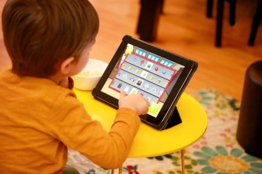 Çocuk evde yatakta Tablet PC'yi kullanma. Divan sevimli çocuk çizgi film izlemek, oyun oynamak ve dizüstü öğrenme. Eğitim, eğlence, eğlence, mutluluk, modern bilgisayar teknoloji ve iletişim.