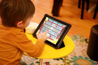 Çocuk evde yatakta Tablet PC'yi kullanma. Divan sevimli çocuk çizgi film izlemek, oyun oynamak ve dizüstü öğrenme. Eğitim, eğlence, eğlence, mutluluk, modern bilgisayar teknoloji ve iletişim.