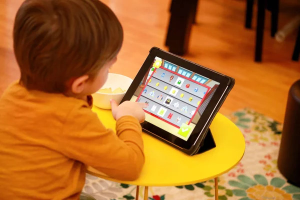 Çocuk evde yatakta Tablet PC'yi kullanma. Divan sevimli çocuk çizgi film izlemek, oyun oynamak ve dizüstü öğrenme. Eğitim, eğlence, eğlence, mutluluk, modern bilgisayar teknoloji ve iletişim.