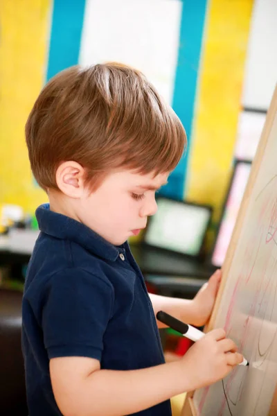 Dziecko jest rysowanie i malowanie z filcu długopis na papierze drewnianej deski do rysowania sztalakowy artysty dla dzieci i dzieci w domu. Dzieciństwa. Cute Little Boy, dziecko rysuje ołówek i kolorowe markery w przedszkolu. — Zdjęcie stockowe