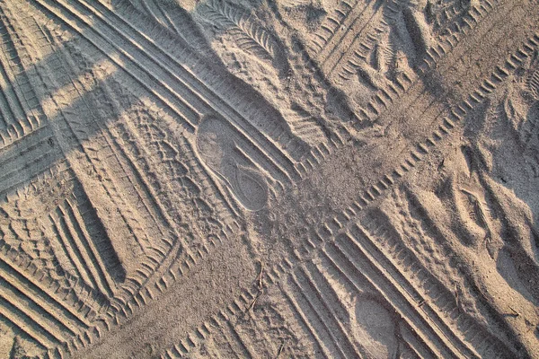 Vestígios na areia. Parte de estampas e pegadas de pneu, pé, pés, chinelos de mar de sol em areia de praia. Textura, material, padrão, fundo e papel de parede de areia. Via de cruzamento do veículo em areia macia . — Fotografia de Stock