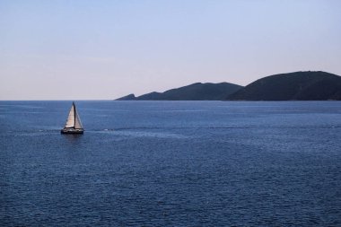 Yalnız gemi, açık denizde yelkenli. Sakin deniz huzurlu bir ortamda en iyi yelken sağlar. Turkuaz denizde küçük bir yelkenli. Güzel manzara, doğal çevre. Yaz sezonu, seyahat, tatil, tatil.