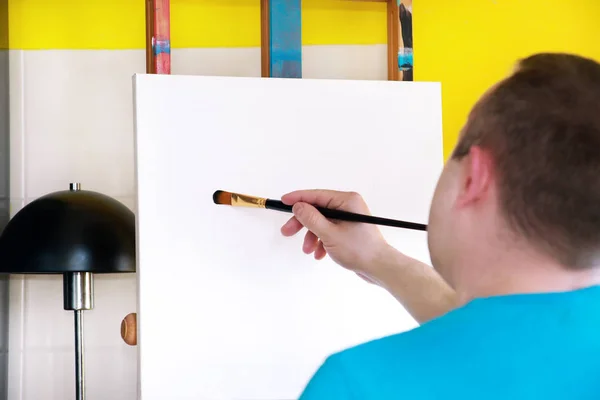 Férfi művész festő dolgozik workshop vászonra fa rajztábla festőállvány Art Paint stúdióban. Portré művész ecsetet festés vászon olajfestékkel. Kreativitási koncepció. — Stock Fotó