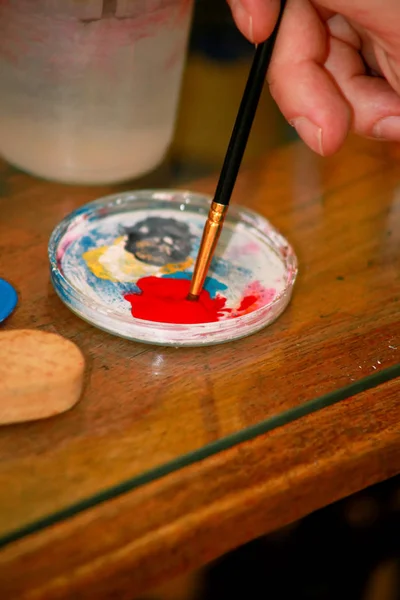 Homem pintor está misturando cores antes de pintar no estúdio de pintura de arte. Artista em sua mão segurando tintas a óleo de cor misturada pincel para pintura na paleta, equipamentos artísticos, close-up. Conceito de criatividade . — Fotografia de Stock
