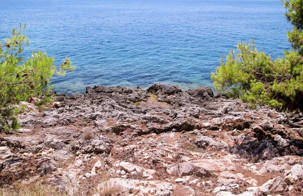 Tenger partja és strand sziklák, sziklás tengerpart, kék tenger, jó napsütéses nap. Nyári kirándulás. Gyönyörű Görögország. Legszebb strand, természeti környezet, hullámok és trópusi táj, horizont és panoráma. — Stock Fotó