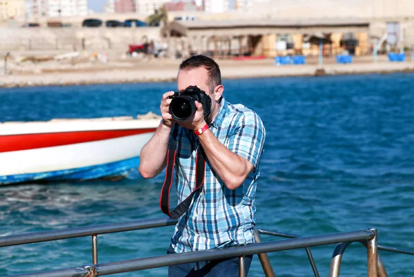 Fotografo professionista, turista e viaggiatore sul molo del mare sta fotografando l'ambiente, la costa del mare. Uomo in vacanza in hotel resort sulla piattaforma spiaggia, che fa fotografia di paesaggio con la macchina fotografica . — Foto Stock