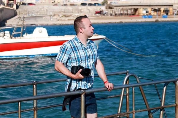 Profesyonel fotoğrafçı, turist ve deniz iskelesi üzerinde seyahat çevre, deniz kıyısında fotoğraf çekiyor. Plaj platformunda otel tatil beldesinde tatiladam, o kamera ile manzara fotoğrafçılığı yapıyor. — Stok fotoğraf