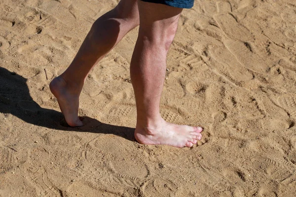 Pernas de homem na areia. Os pés masculinos que andam na praia arenosa bonita do recurso do hotel no mar vermelho em Egipto, fazendo e deixam para trás pegadas na areia. Um homem de férias no Verão. Conceito de viagem e férias . — Fotografia de Stock