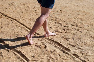 Kumda erkek bacakları. Erkek ayakları Mısır'da Kızıldeniz'de otel tesisi güzel kumlu plajda yürüyüş yapıyor ve kum ayak izleri geride bırakın. Yaz ları tatilde olan adam. Seyahat ve tatil konsepti.