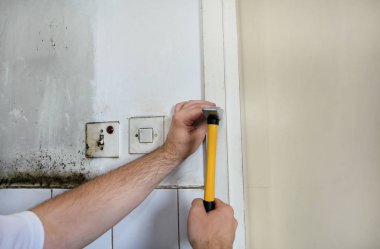 İnşaat işçisi ve tadilat çalışmaları üzerinde çalışan işçi. Sarı çekiç grevler ve çivi ler ile Builder inşaat yerinde mutfak kapısının ahşap duvara bir çivi. Apartman yenileme konsepti.