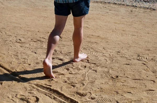 Man legs on sand. Male feet walking on beautiful sandy beach of hotel resort on Red sea in Egypt, doing and leave behind footprints in sand. Man on vacation in summertime. Travel and holiday concept. — Stock Photo, Image