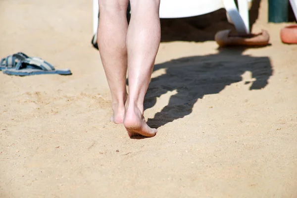 Jambes d'homme sur sable. Pieds masculins marchant sur la belle plage de sable fin de la station hôtelière sur la mer Rouge en Egypte, faire et laisser des empreintes de pas dans le sable. Homme en vacances en été. Concept de voyage et vacances . — Photo