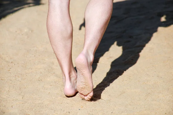 Jambes d'homme sur sable. Pieds masculins marchant sur la belle plage de sable fin de la station hôtelière sur la mer Rouge en Egypte, faire et laisser des empreintes de pas dans le sable. Homme en vacances en été. Concept de voyage et vacances . — Photo
