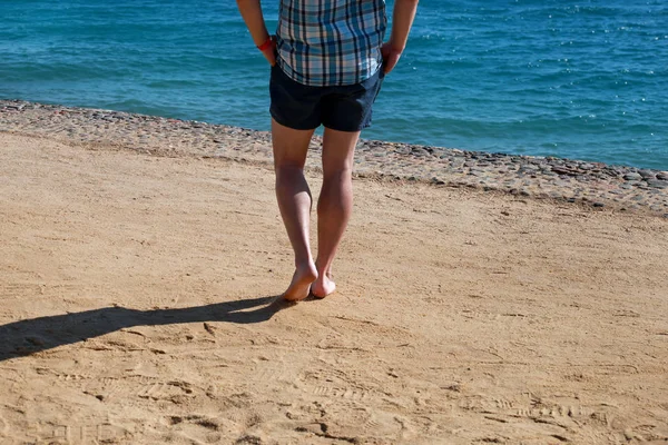 Patas de hombre sobre arena. Pies masculinos caminando en la hermosa playa de arena del complejo hotelero en el Mar Rojo en Egipto, haciendo y dejando huellas en la arena. Un hombre de vacaciones en verano. Concepto de viaje y vacaciones . —  Fotos de Stock