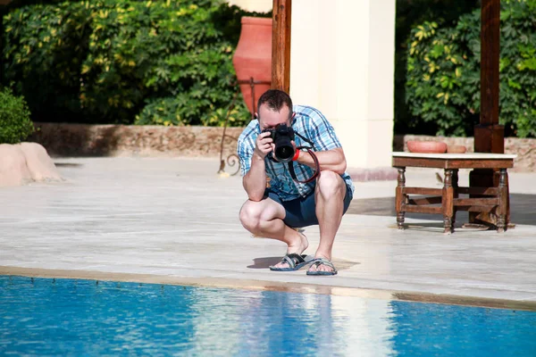 Profesyonel fotoğrafçı, turist ve otel resort yüzme havuzu nda gezgin, o fotoğraf çekerek, kamera ile su ve çevre fotoğrafçılığı yapıyor. Yakışıklı adam yaz tatilde. — Stok fotoğraf