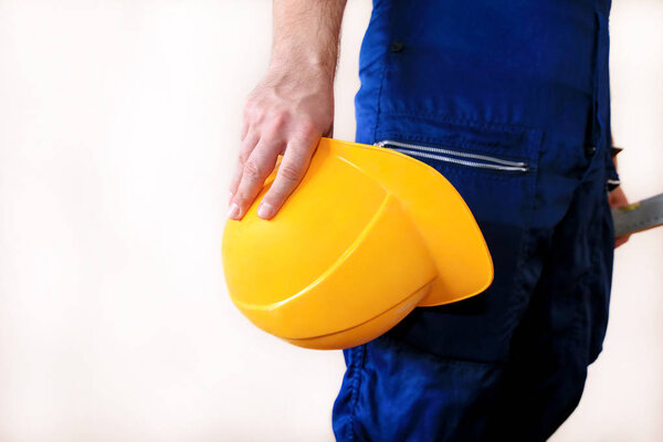 Строитель и мастер работает над ремонтом квартиры. Строитель на строительной площадке в защитной форме и снаряжении, он с костюмом, покрывалом и желтым шлемом держит в руке
.