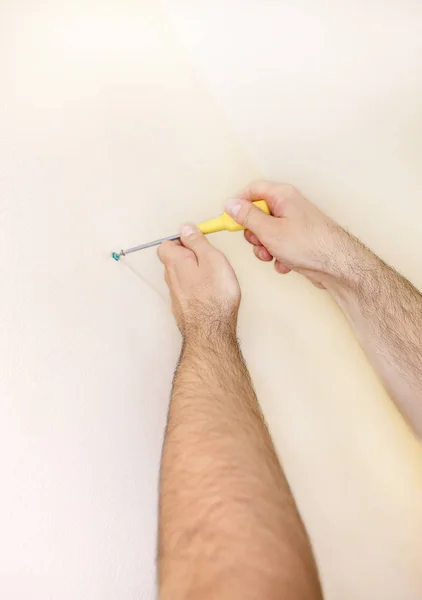 Operaio edile e tuttofare lavora sulla ristrutturazione di appartamento. Costruttore utilizzando viti gialle cacciavite vite in acciaio dal muro in cantiere. Concetto di ristrutturazione della casa. Strumento di costruzione . — Foto Stock