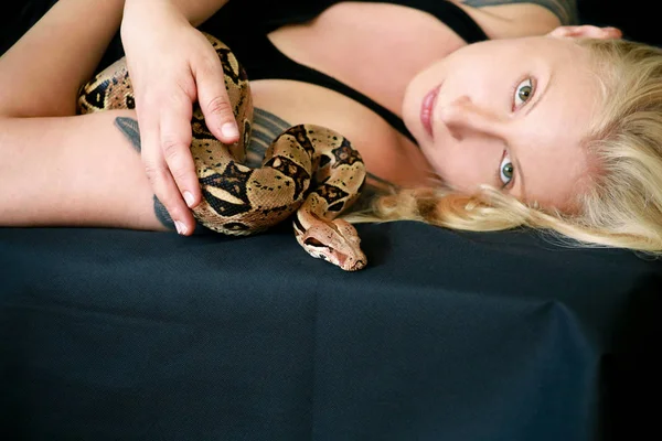 Porträt eines Mädchens mit Boa Constrictor Schlange. schöne Frau hält Schlange in den Händen und posiert vor der Kamera. exotisches tropisches Kaltblüterreptil, ungiftige Schlangenart Boa constrictor. — Stockfoto