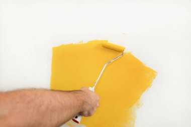 İnşaat işçisi ve tamirci dairede tadilat yapıyor. Profesyonel ressam, inşaat alanında sarı renkli duvar fırçası boyası kullanıyor. Ev yenileme konsepti.