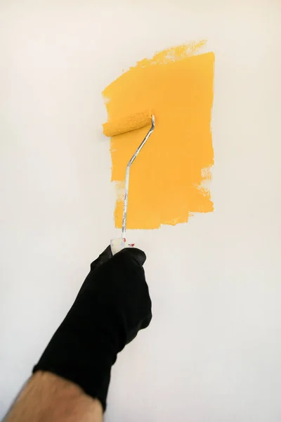 Operaio edile e tuttofare fare finire la ristrutturazione in appartamento. Pittore professionista che utilizza pittura pennello rullo vernice della parete con colore giallo in cantiere. Concetto di ristrutturazione casa . — Foto Stock