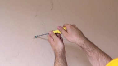 İnşaat işçisi ve tamirci daire yenileme çalışmaları. İnşaat sahasında duvardan çıkan sarı tornavida vidaları kullanan inşaatçı. Ev yenileme konsepti. İnşaat aleti.
