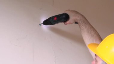 İnşaat işçisi ve tamirci dairenin tadilatı üzerinde çalışıyor. İnşaatçı inşaat alanında elektrikli tornavida ve vida kullanıyor. Ev yenileme konsepti. Yapı aracı.