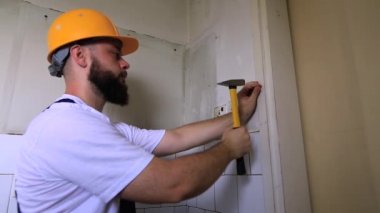 İnşaat işçisi ve tadilat çalışmaları üzerinde çalışan işçi. Sarı çekiç grevler ve çivi ler ile Builder inşaat yerinde mutfak kapısının ahşap duvara bir çivi. Apartman yenileme konsepti.