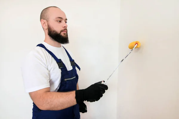 Trabajador de la construcción y manitas haciendo renovación de acabado en el apartamento. Pintor profesional que utiliza la pintura del pincel del rodillo de la pintura de la pared con color amarillo en sitio de construcción. Concepto de renovación del hogar . — Foto de Stock