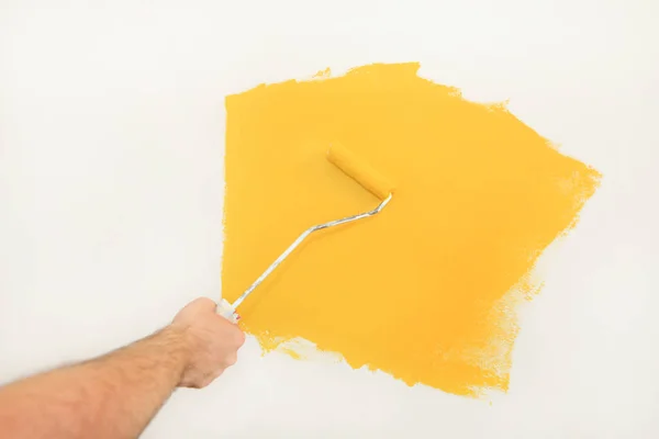 Operaio edile e tuttofare fare finire la ristrutturazione in appartamento. Pittore professionista che utilizza pittura pennello rullo vernice della parete con colore giallo in cantiere. Concetto di ristrutturazione casa . — Foto Stock