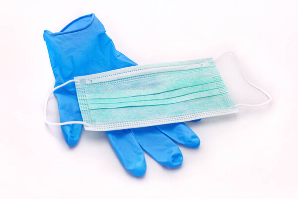 Пара медицинских синих латексных защитных перчаток и зеленая маска на белом фоне. Защитное оборудование против вируса, гриппа, коронавируса (COVID-19), бактерий и микробов. Здравоохранение и хирургическая концепция.