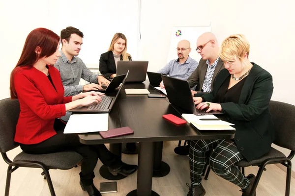 Business men and women at the meeting. Corporate group. Full concentration at work. Group of business people working and communicating while sitting at office desk together with colleagues sitting.