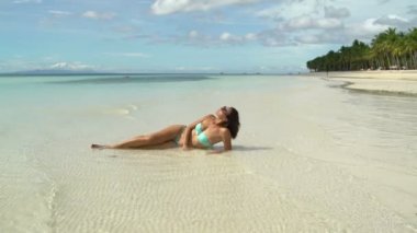 Midesini sahilde bir mayo içinde bir kadın yatıyor