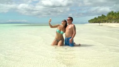 Bir adam bir kadınla selfi denizde yapar