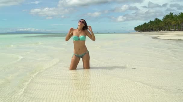 Une femme en maillot de bain est agenouillée dans la mer et bronzant — Video