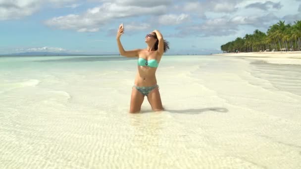 Een vrouw in een zwembroek maakt een selfie op de kust — Stockvideo