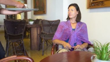 Bir kadın kafeteryada bir masada oturuyor. Garson kahve getiriyor