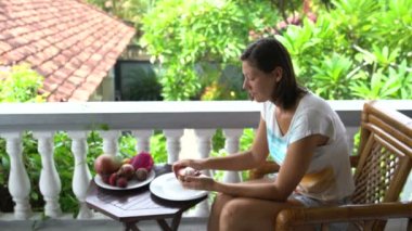 Balkonda oturan mangosten keser kadınve yiyor